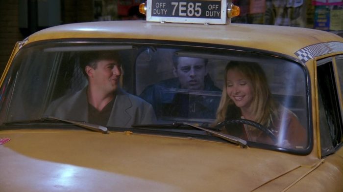 Phoebe, Joey, and Chandler sitting in a taxi for a Christmas road trip.