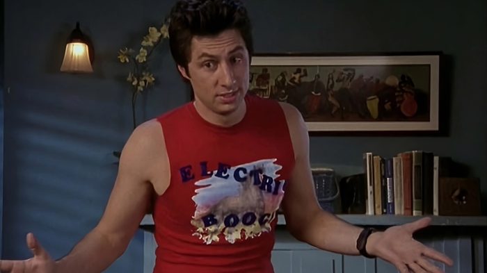 D wearing a tight red "Electric Boogaloo" sleeveless shirt with his arms spread wide.